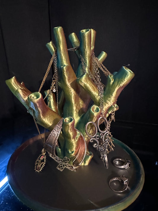 Jewelry holder with green metallic finish displaying necklaces and rings on a dark background